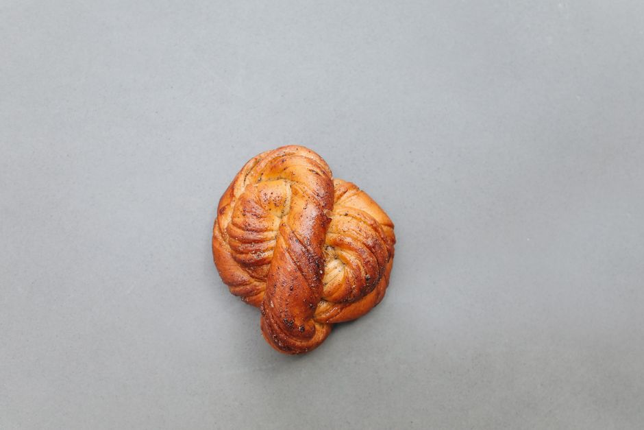 Close-up of a fresh homemade Swedish cardamom bun on a neutral background.